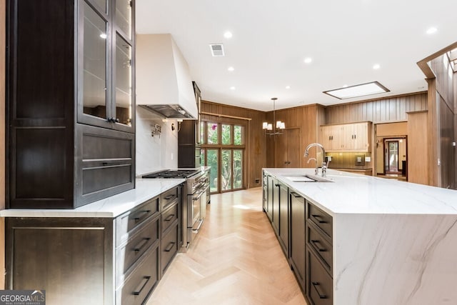 kitchen featuring decorative light fixtures, custom exhaust hood, sink, double oven range, and light stone counters