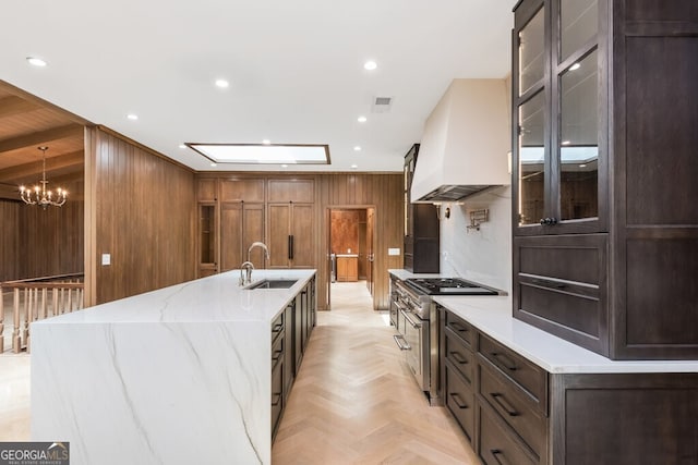 kitchen featuring custom exhaust hood, hanging light fixtures, sink, double oven range, and light stone countertops