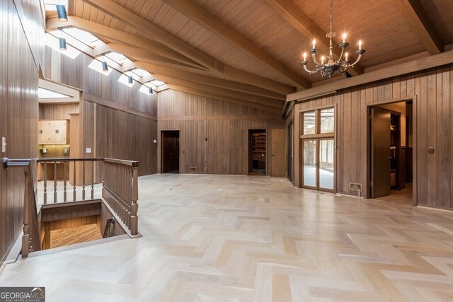 unfurnished room featuring light parquet floors, wood walls, and a chandelier