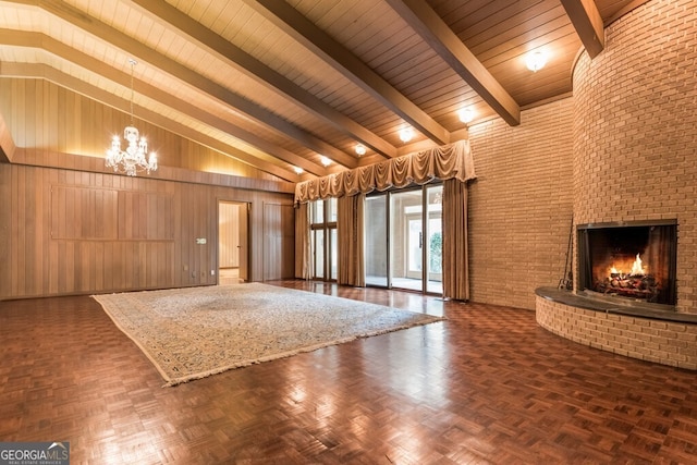 unfurnished living room featuring a fireplace, a chandelier, high vaulted ceiling, beamed ceiling, and wood walls