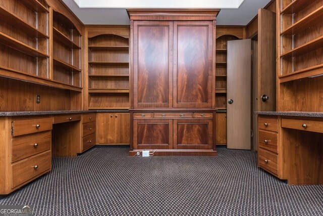 unfurnished office with dark colored carpet and built in desk