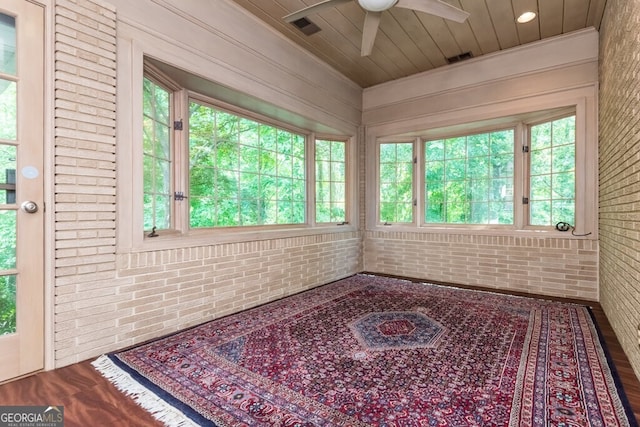 spare room with brick wall, a wealth of natural light, hardwood / wood-style flooring, and ceiling fan