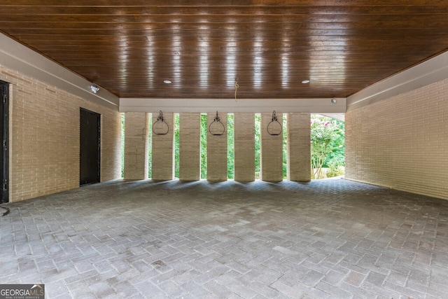 unfurnished room featuring wood ceiling and brick wall