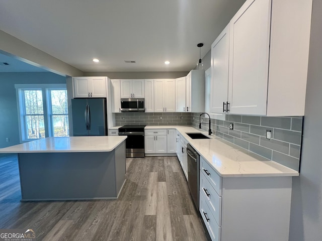 kitchen featuring sink, backsplash, pendant lighting, white cabinets, and appliances with stainless steel finishes