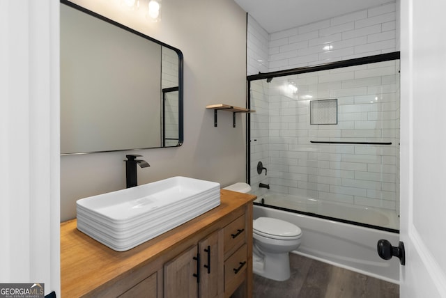 full bathroom with vanity, shower / bath combination with glass door, wood finished floors, and toilet