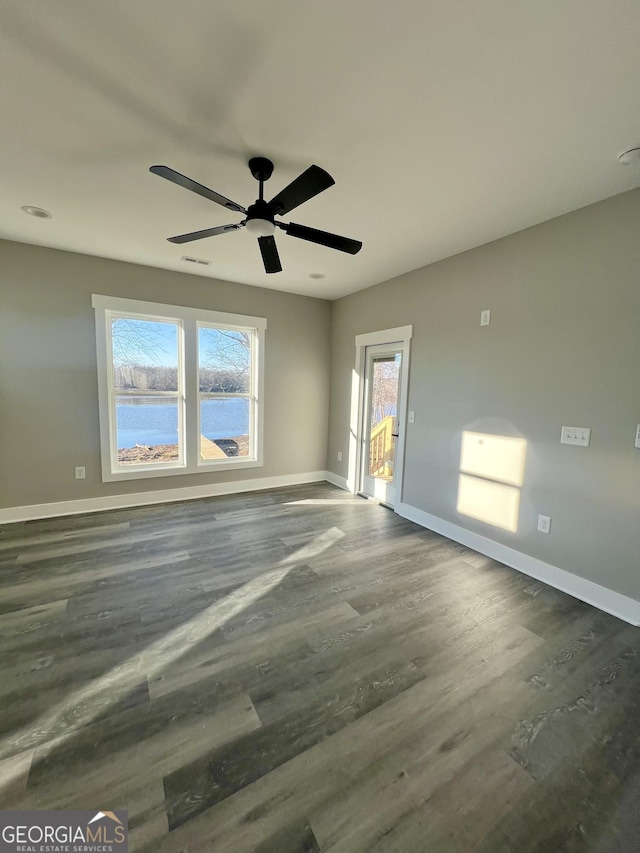 spare room featuring ceiling fan, a water view, and dark wood-type flooring