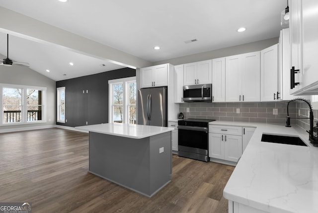 kitchen with a center island, visible vents, appliances with stainless steel finishes, open floor plan, and a sink