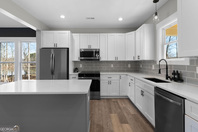 kitchen featuring dark wood finished floors, stainless steel appliances, light countertops, visible vents, and a sink