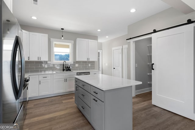 kitchen featuring dark wood-type flooring, appliances with stainless steel finishes, a barn door, and a sink