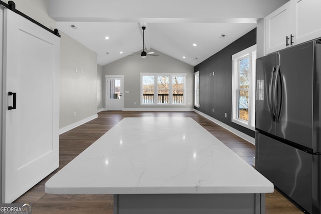 kitchen with a barn door, dark wood-type flooring, a kitchen island, white cabinets, and freestanding refrigerator