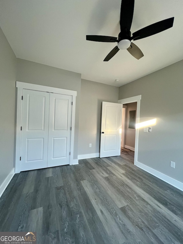 unfurnished bedroom featuring dark hardwood / wood-style flooring, ceiling fan, and a closet