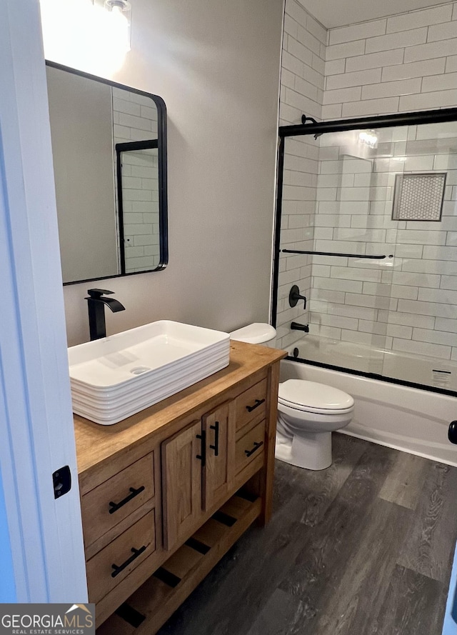 full bathroom with wood-type flooring, vanity, toilet, and enclosed tub / shower combo