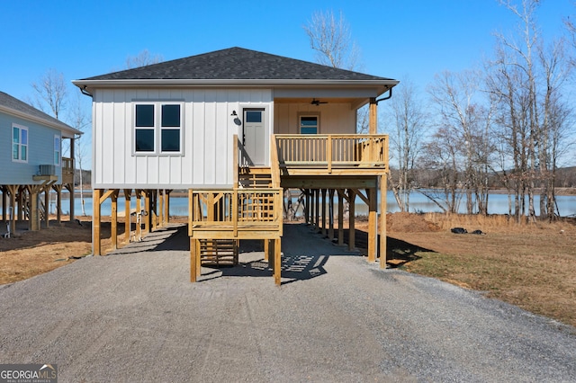 coastal inspired home featuring driveway, a water view, a shingled roof, and a carport