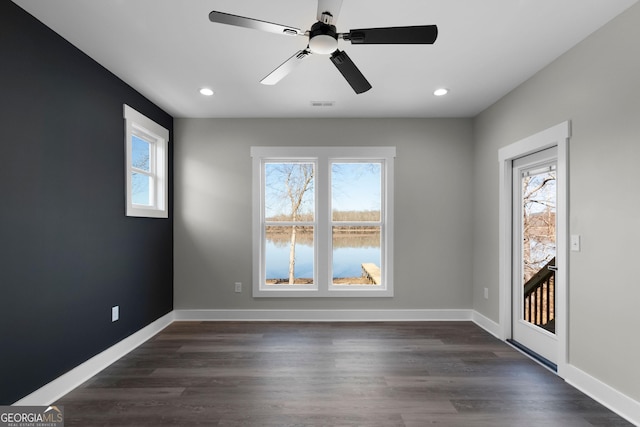 empty room featuring baseboards, dark wood-type flooring, and a healthy amount of sunlight