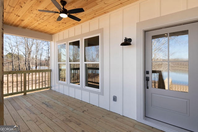 wooden deck with a water view and a ceiling fan