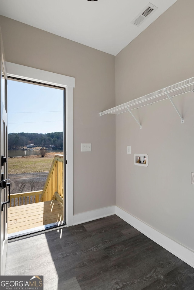 washroom with washer hookup, baseboards, visible vents, and wood finished floors