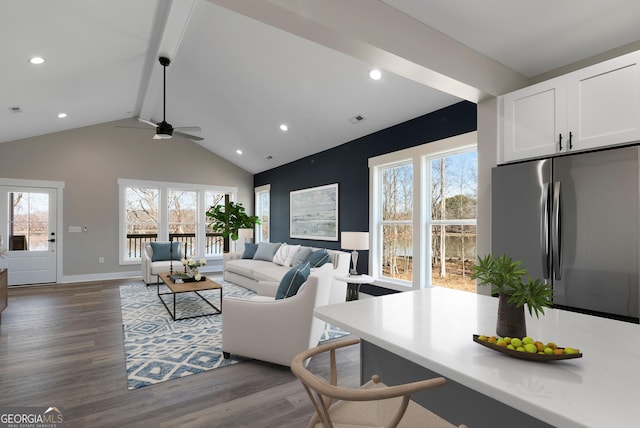 living area featuring dark wood-type flooring, plenty of natural light, visible vents, and beamed ceiling