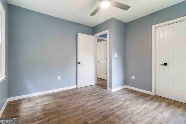 unfurnished bedroom with a closet, hardwood / wood-style floors, and ceiling fan