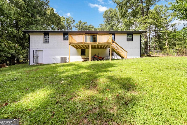 rear view of property featuring a lawn, central AC unit, and a wooden deck