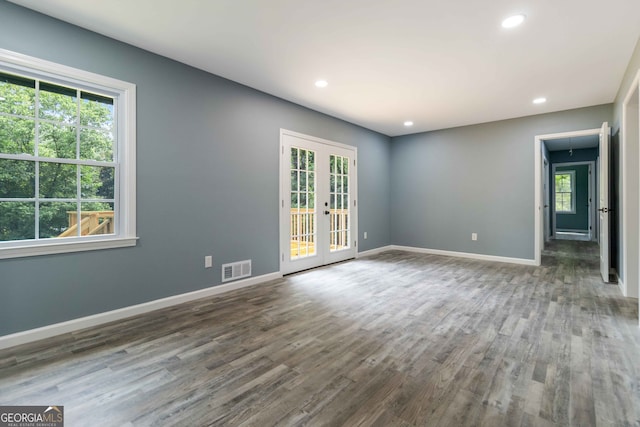 empty room with french doors, dark hardwood / wood-style flooring, and a wealth of natural light