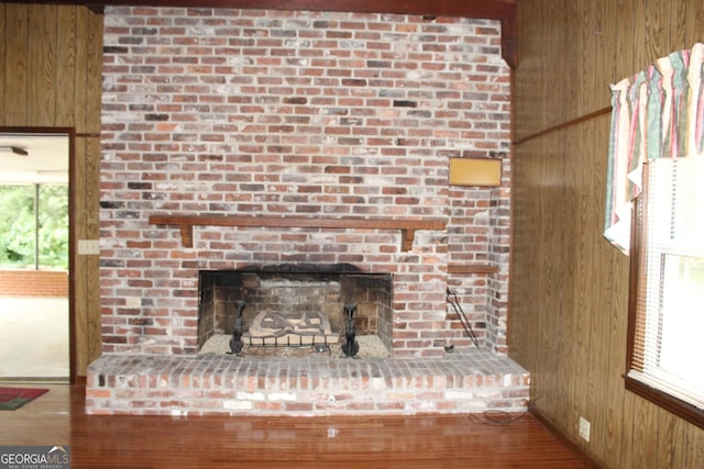 interior details featuring wood-type flooring, a brick fireplace, and wooden walls