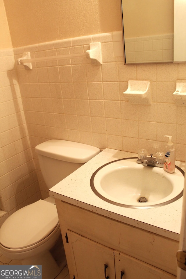 bathroom featuring vanity, tile walls, and toilet