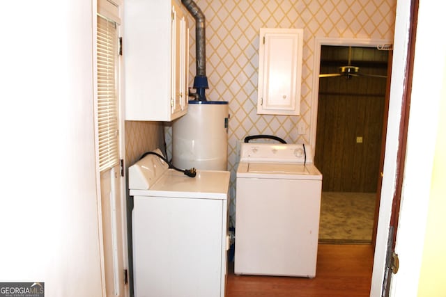 clothes washing area featuring cabinets, washer and clothes dryer, hardwood / wood-style floors, and water heater