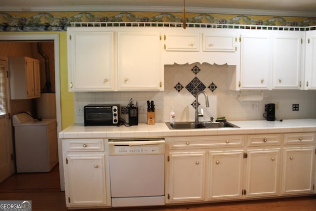 kitchen featuring sink, backsplash, white dishwasher, tile counters, and washer / dryer