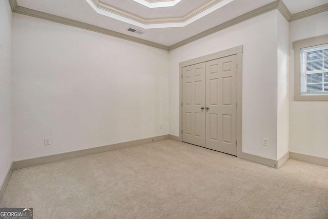 unfurnished bedroom with crown molding, a closet, and light colored carpet