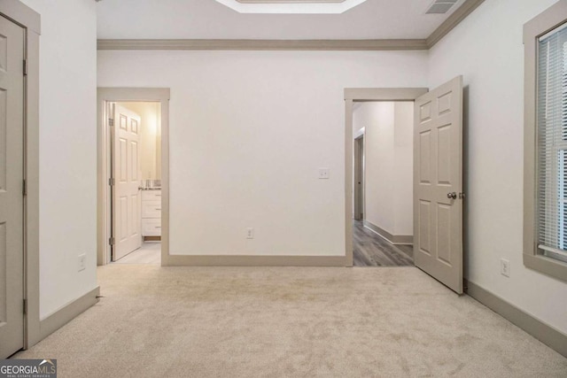 unfurnished bedroom with connected bathroom, light colored carpet, and ornamental molding