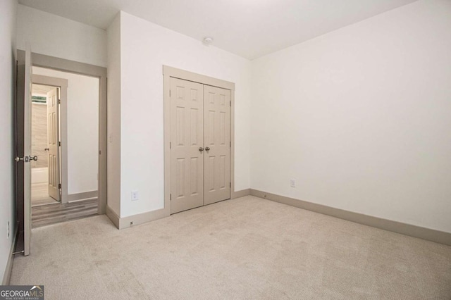 unfurnished bedroom featuring light carpet and a closet