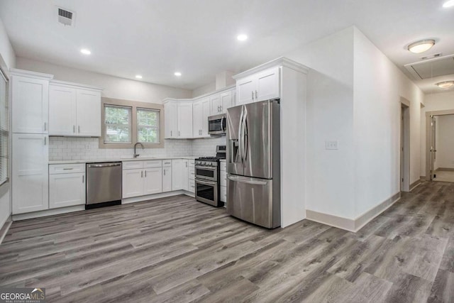 kitchen featuring backsplash, sink, light wood-type flooring, white cabinetry, and stainless steel appliances