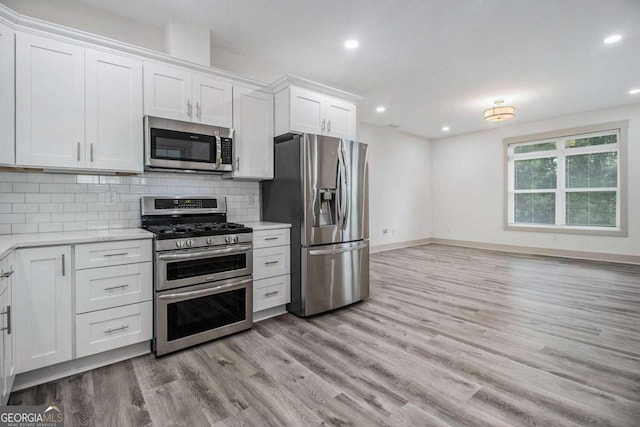 kitchen featuring white cabinets, appliances with stainless steel finishes, light wood-type flooring, and tasteful backsplash