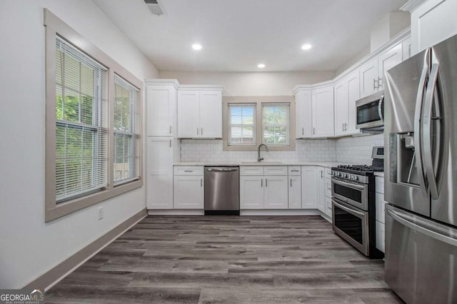 kitchen featuring sink, backsplash, plenty of natural light, white cabinets, and appliances with stainless steel finishes