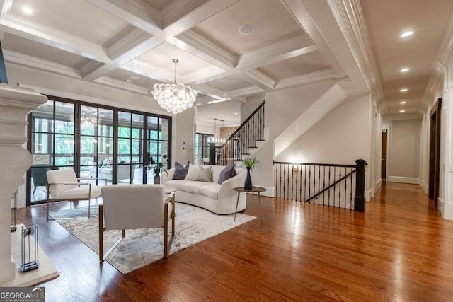 living room featuring coffered ceiling, an inviting chandelier, crown molding, and beamed ceiling