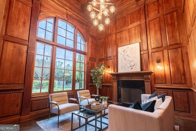 sitting room featuring a high ceiling, a chandelier, wooden walls, and dark parquet floors