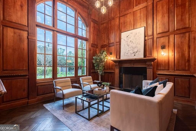 living area with a towering ceiling, parquet flooring, and wood walls