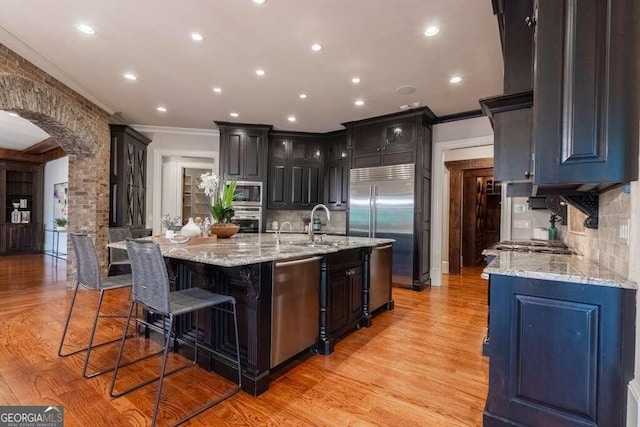 kitchen featuring ornamental molding, built in appliances, decorative backsplash, and a spacious island