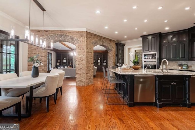 kitchen with appliances with stainless steel finishes, light hardwood / wood-style floors, decorative light fixtures, and ornamental molding