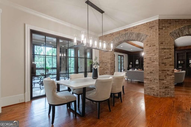 dining room featuring ornamental molding, hardwood / wood-style floors, and brick wall