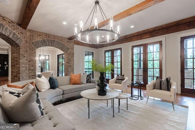 living room featuring brick wall, an inviting chandelier, french doors, and beamed ceiling