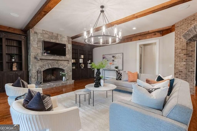 living room with beamed ceiling, a fireplace, hardwood / wood-style flooring, an inviting chandelier, and built in shelves