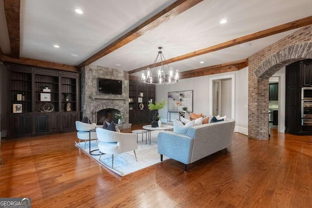 living room featuring a fireplace, a chandelier, hardwood / wood-style flooring, and beamed ceiling