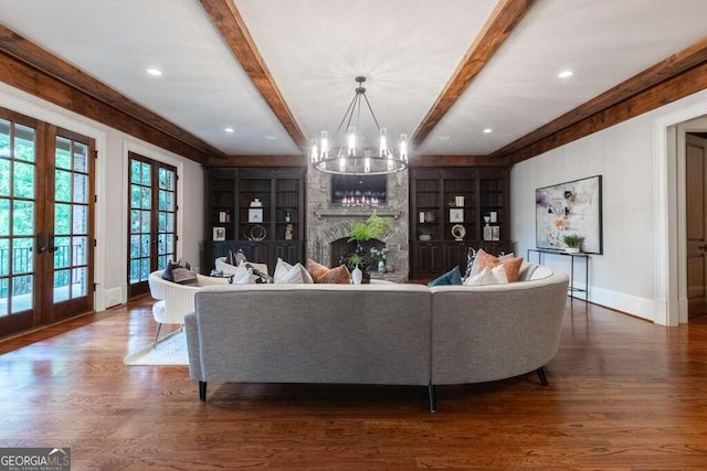 living room featuring a stone fireplace, wood-type flooring, french doors, an inviting chandelier, and built in features