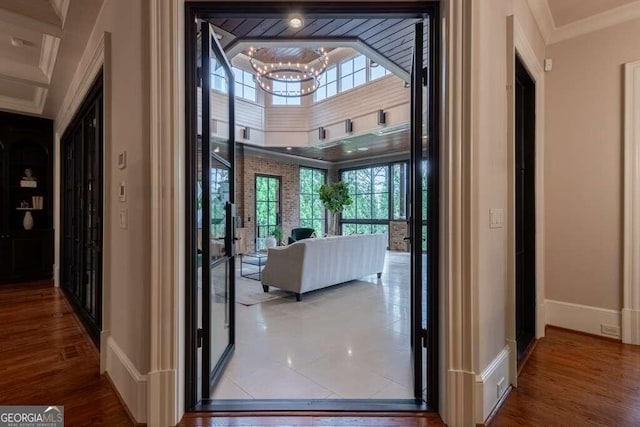 hallway featuring hardwood / wood-style flooring, a chandelier, ornamental molding, and a healthy amount of sunlight