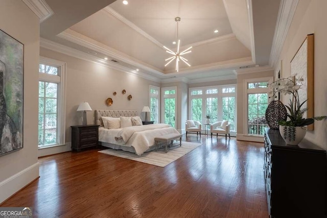 bedroom featuring dark wood-type flooring, an inviting chandelier, a tray ceiling, and crown molding