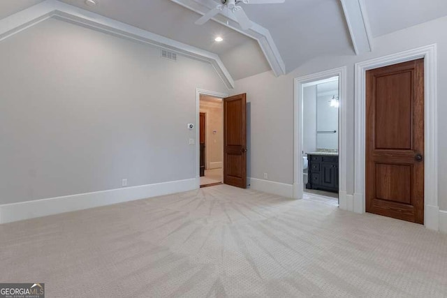 interior space featuring lofted ceiling, ensuite bath, light colored carpet, and ceiling fan