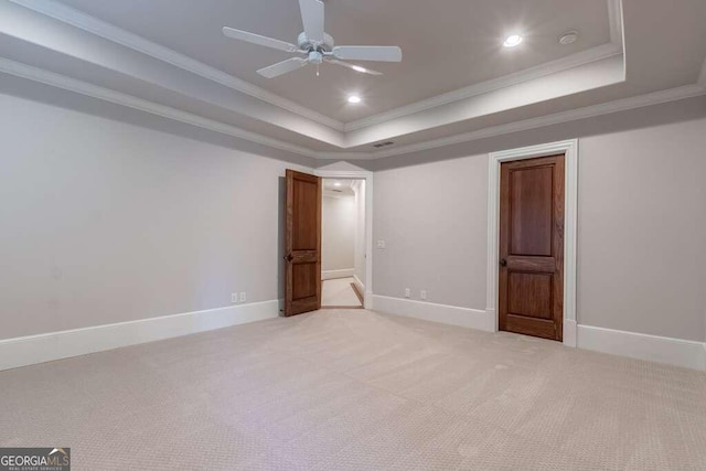 interior space with a raised ceiling, light carpet, ceiling fan, and ornamental molding