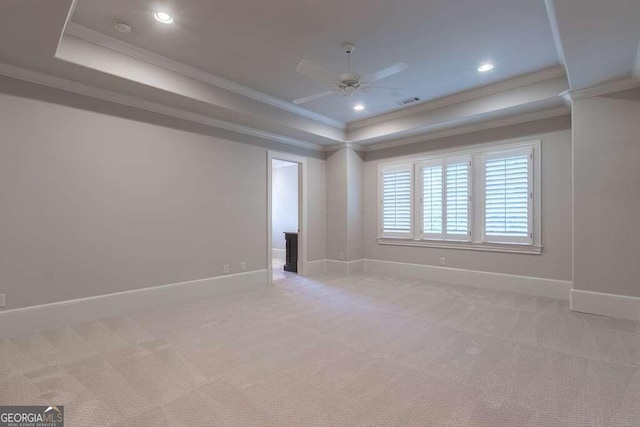 spare room featuring ornamental molding, light colored carpet, a raised ceiling, and ceiling fan