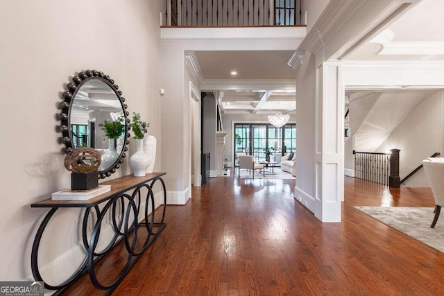 foyer entrance with beamed ceiling, coffered ceiling, dark hardwood / wood-style flooring, crown molding, and a notable chandelier